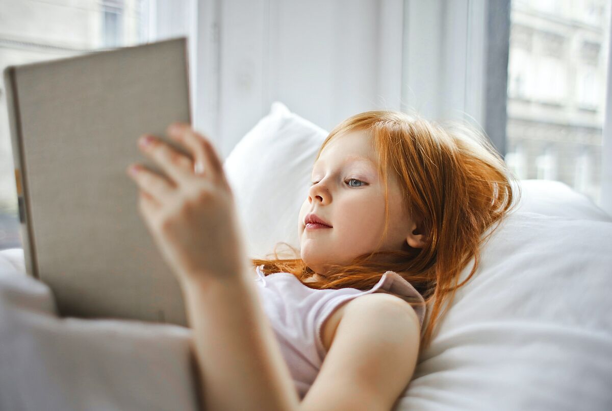 Mädchen liest auf dem Bett liegend ein Buch @pexels.com