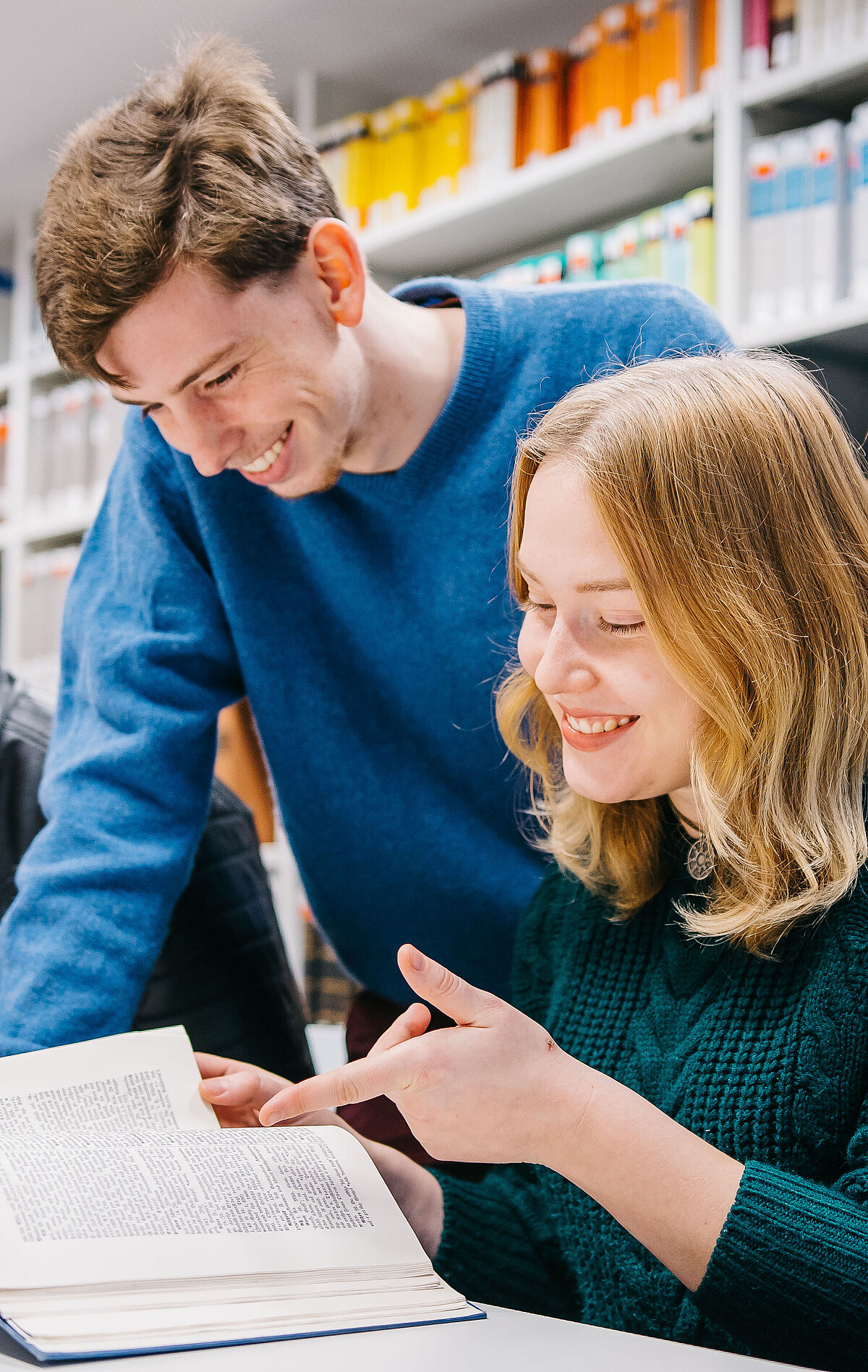 Symbolbild Marketing Baltistik: Mehrere Personen sitzen in einer Bibliothek und schauen in Bücher.